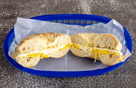 A sliced bagel sandwich with egg and melted cheese is placed on parchment paper in a blue plastic basket.