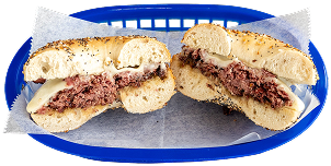 Bagel sandwich with a beef patty and melted cheese, sliced in half, served in a blue plastic basket lined with parchment paper.