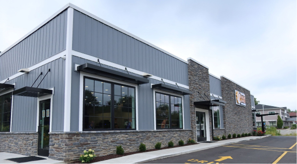 Exterior of a gray-sided restaurant building with stone accents and a drive-thru lane.